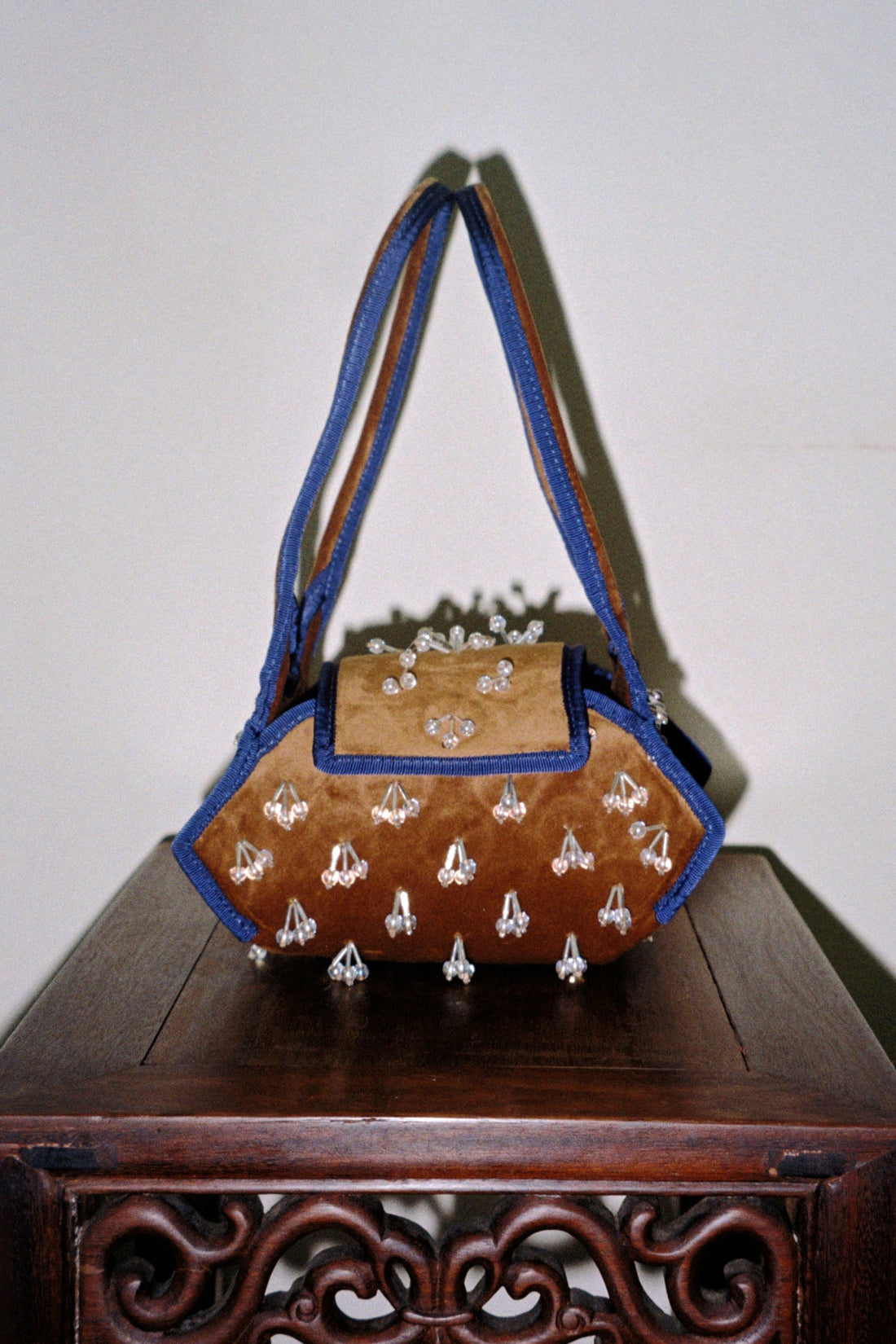 Brown handbag with blue accents on a wooden surface