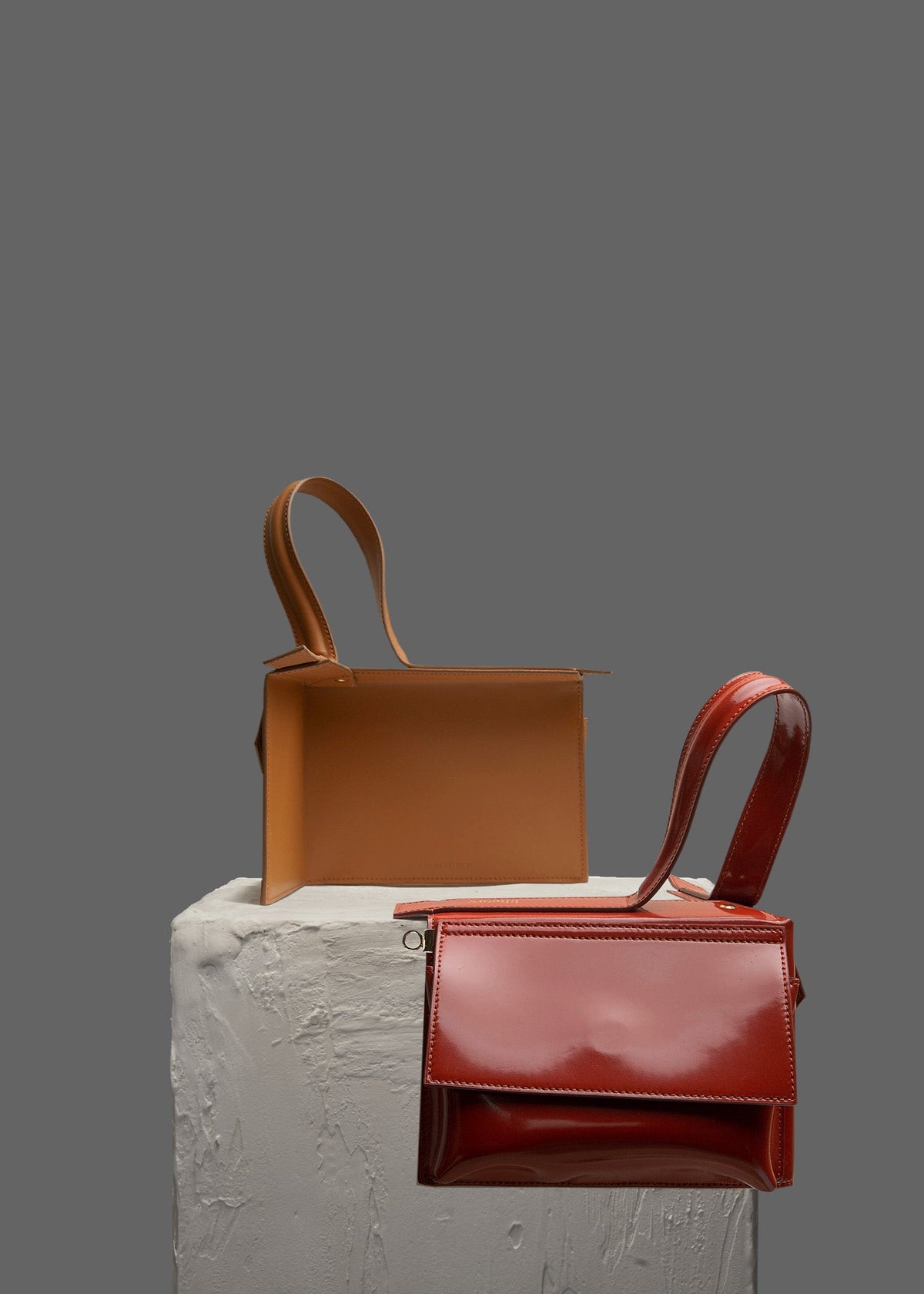The Corner Guard Leather Handbag in color Rust sitting on a stand
