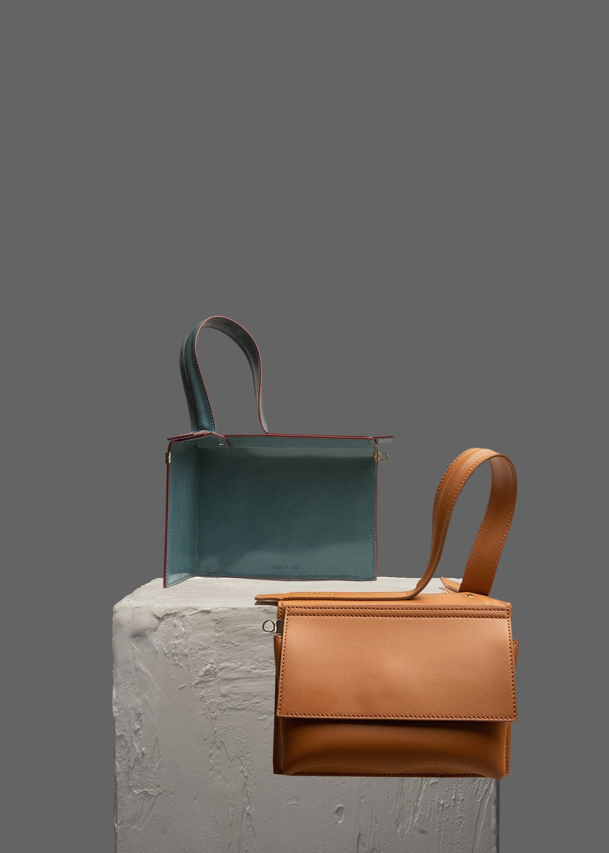 The Corner Guard Leather Handbag in color Tan sitting on a stand
