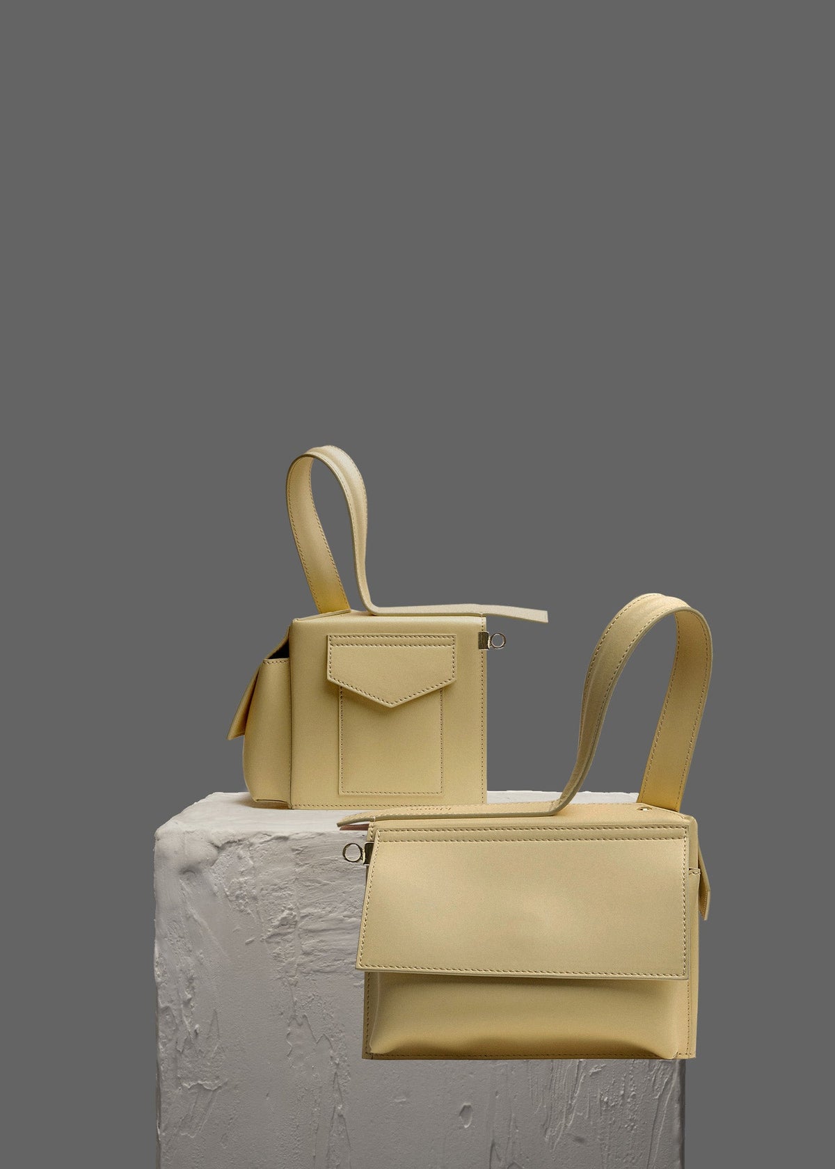 The Corner Guard Leather Handbag in color Eggshell Yellow sitting on a stand